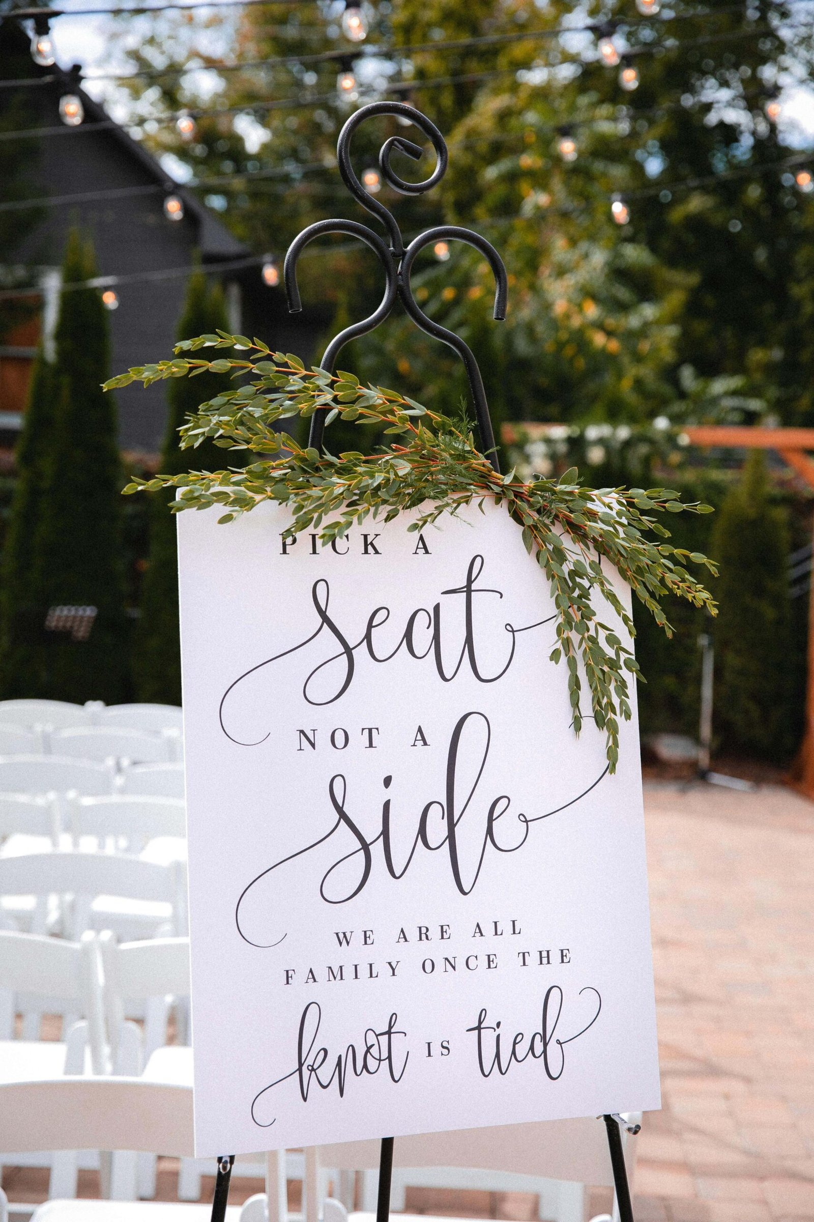 Image of a sign at a wedding stating "Pick a seat, not a side - we are all family once the knot is tied." - www.iamacelebrant.uk