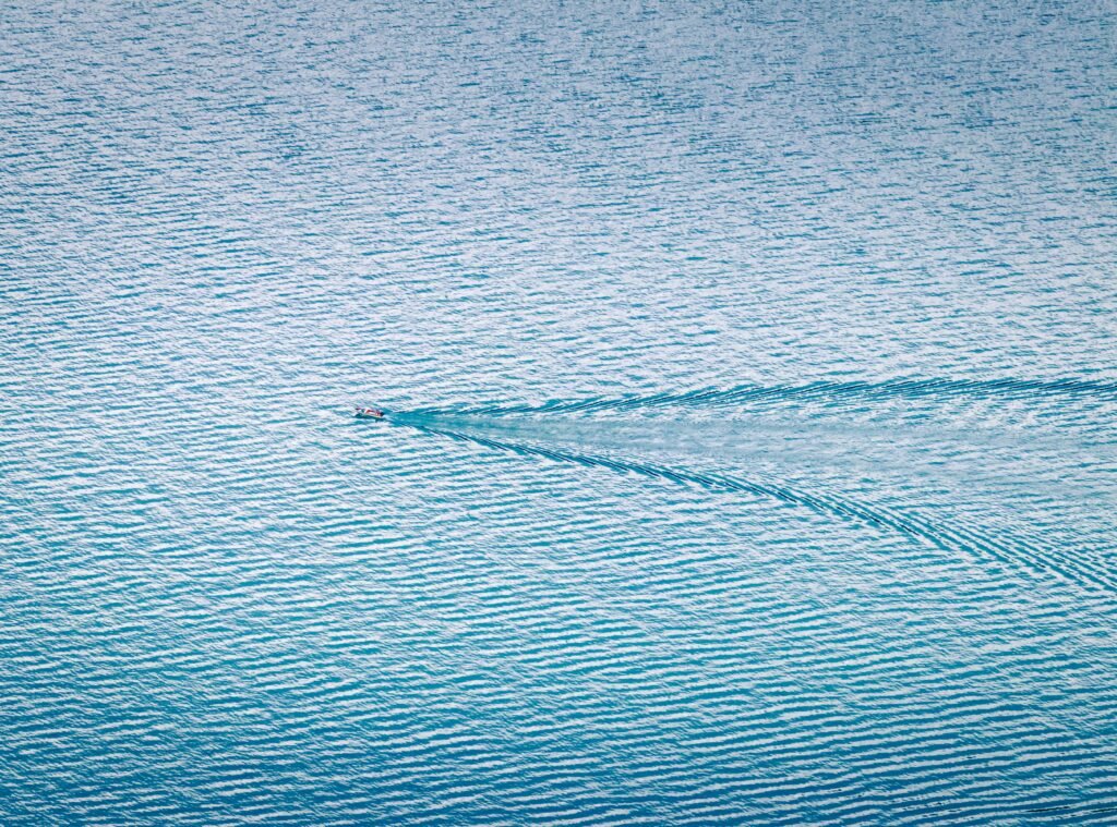 A boat crosses a lake showing its wake fanning out across the water... symbolising the wake of a life...